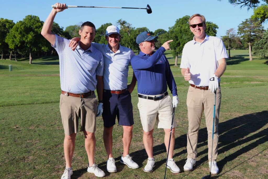 men smiling and holding golf clubs