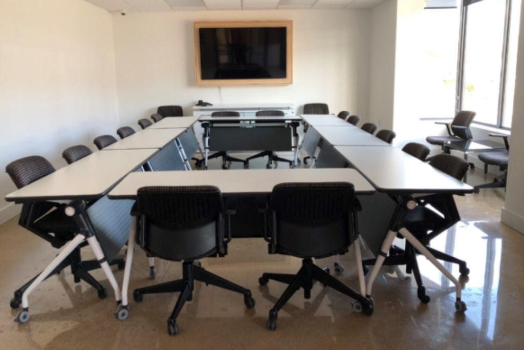 conference room with tables, chairs, and tv on the wall