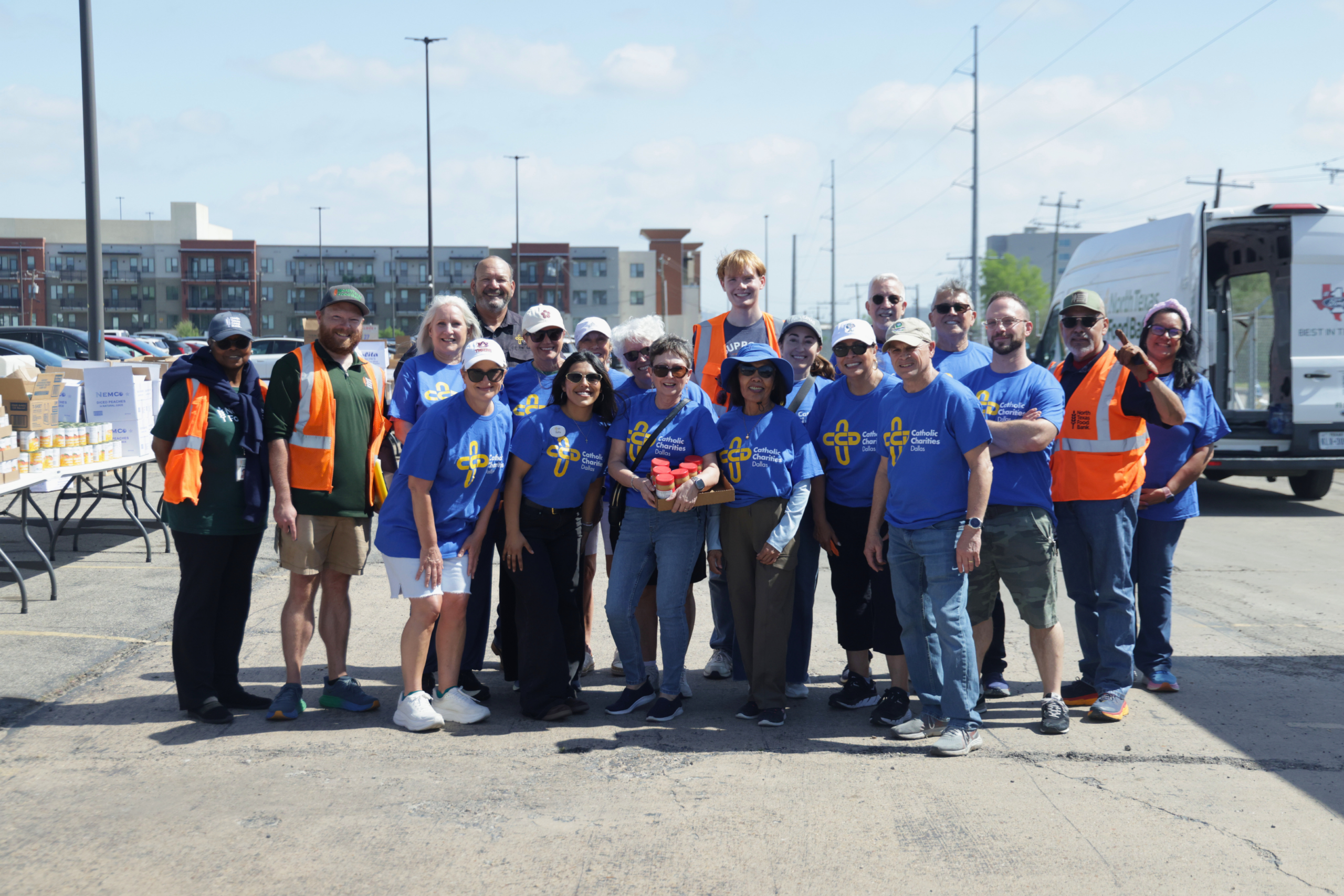 large group of volunteers from different organizations stand together smiling after distributing food